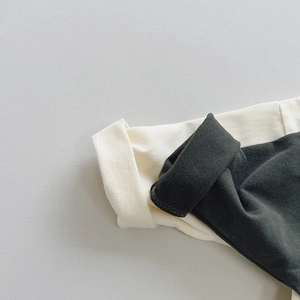 Close-up of ribbed cuffs on cotton cartoon t-shirts in cream and dark gray colors