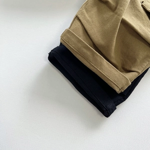 Dettaglio di pantaloni cargo in cotone kaki e nero con doppie cuciture sul bordo