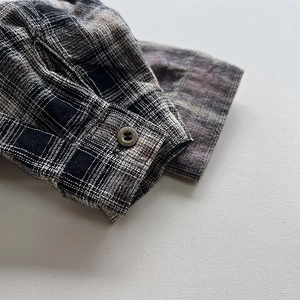 Close-up of boys' plaid shirt cuff with dark button and soft flannel fabric texture