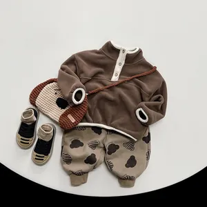 Flat lay of brown fleece top and bear print trousers for children's winter outfit