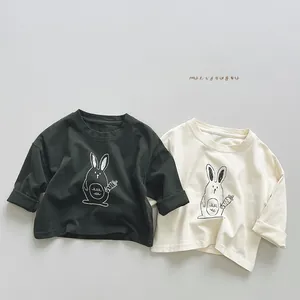 Close-up of olive green and cream cotton t-shirts featuring hand-drawn rabbit graphics