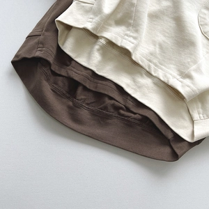 Détail de l'ourlet à double aiguille sur t-shirts enfant en coton crème et marron