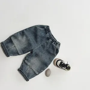 Flat lay of dark blue washed denim jeans for children with an elastic waistband and sneakers