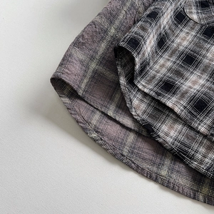 Close-up of boys plaid shirt featuring curved hem and high-quality woven fabric detail