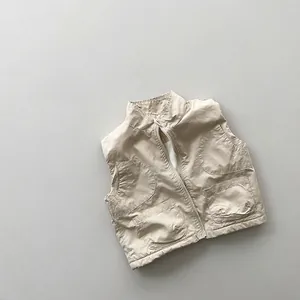 Close-up of beige quilted kids' vest showing front zipper and functional four-pocket design