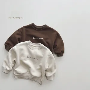 Detail of fleece-lined kids sweatshirts in brown and cream with ribbed cuffs and hem