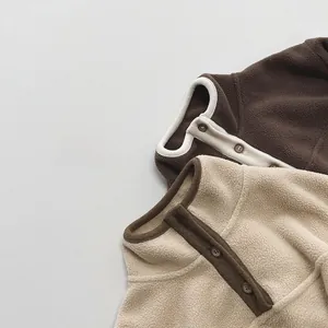 Detail of warm polar fleece kids sweatshirts with button collar in brown and beige colors