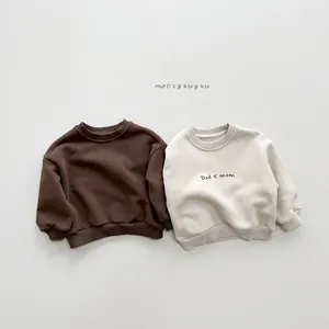 Detail of baby fleece sweatshirts in brown and cream with Dad < mom printed lettering