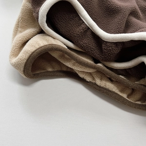 Close-up of soft fleece fabric detail with contrast binding in brown and beige tones