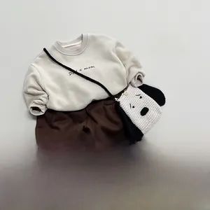 Flat lay of beige sweatshirt with brown trousers and a cute puppy crossbody bag