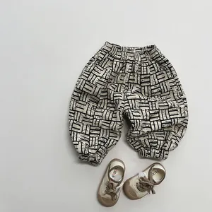 Détail d'un pantalon en polaire à motifs géométriques et chaussures en toile beige pour bébé