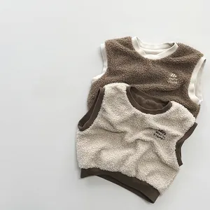 Detail of soft fleece kid vests featuring warm vibes embroidery and contrast trim