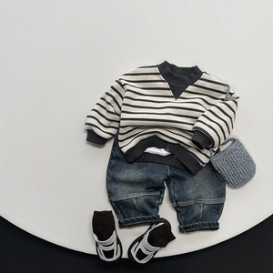 Flat lay of striped sweatshirt and washed denim jeans set for kids in minimalist style