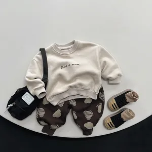 Detailed flat lay of beige kids sweatshirt with 'Dad < mom' print and brown bear pants