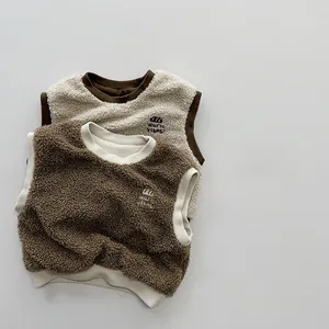 Detail showing plush fleece texture and warm vibes embroidery on kids colorblock vests