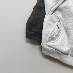 Detail of fleece hoodies showing kangaroo pockets and ribbed cuffs in dark coffee and grey