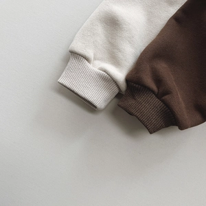 Close-up of ribbed cuffs on thick fleece sweatshirts in cream white and dark brown colors