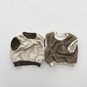 Flat lay of two color-block fleece vests with embroidered details for kids