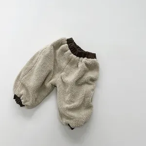 Detailed texture of thick beige lamb velvet pants with brown elastic ribbed waist and cuffs