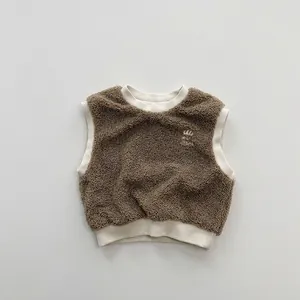 Detail of soft brown sherpa fleece vest with beige ribbed trim and white embroidery