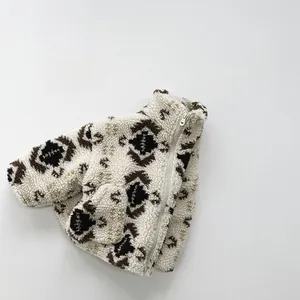 Detail of children fleece jacket with brown geometric patterns and metal zipper
