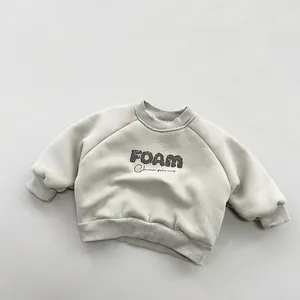 Detail of light beige fleece sweatshirt with ribbed cuffs and FOAM Champions print