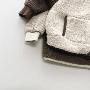 Detail of plush cream fleece fabric and contrast brown knit trim on kids winter vest