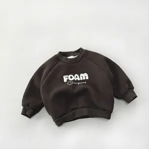 Detail of dark brown kids fleece sweatshirt with white FOAM Champions lettering