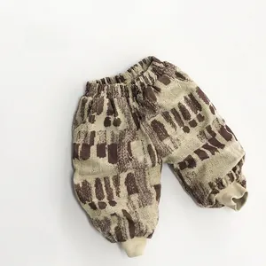 Détail d'un pantalon en velours pour enfant avec motifs abstraits marron et chevilles côtelées