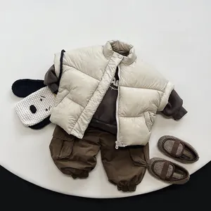 Flat lay of boy's winter beige vest and dark brown cargo pants with dog-shaped bag