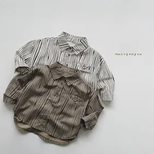 Detail view of striped long-sleeve kids' shirts in cream and khaki with flap pockets