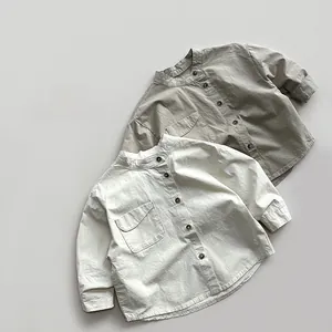 Detail view of cotton kid shirt with stand collar and front chest pocket in beige colors