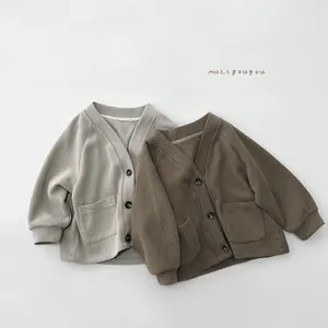 Detail of V-neck knitted cardigans for kids featuring large pockets and ribbed cuffs