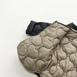 Detail shot of quilted winter jacket fabric with silver snap buttons in khaki and black
