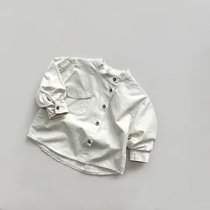 Detail of white cotton long-sleeve kids shirt with stand collar and dark brown button