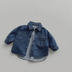 Détail d'une chemise en jean bleu foncé pour enfants avec poches poitrine et boutons