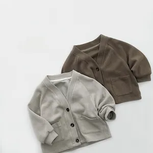 Detail of V-neck knitted cardigans with buttons and square pockets for children