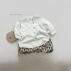 Flat lay of a child's beige cotton shirt with wooden buttons and brown wavy print pants