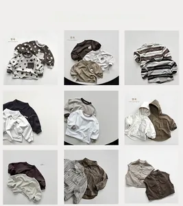 Flat lay collection of boys cotton tops and workwear vests in earthy tones