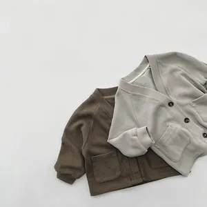 Detail view of V-neck cotton cardigans in brown and grey-green with square pockets