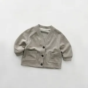 Detail of grey knitted kids cardigan showing V-neckline and dark buttons texture