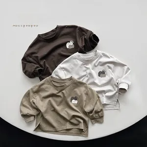 Flat lay of minimalist cotton kids long-sleeved t-shirts with apple print and smooth necklines