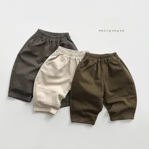 Dettaglio in piano di pantaloni cargo per bambini in grigio, beige e verde militare
