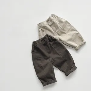 Detail of kids casual cotton trousers featuring elastic waist with button in brown and beige