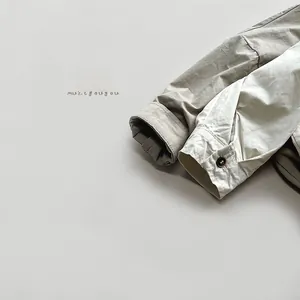 Close-up of cotton cuffs with brown buttons on khaki and cream children shirts