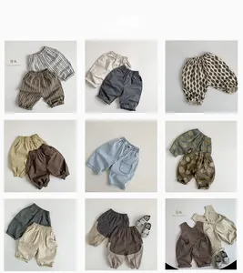 Flat lay grid of nine baby cotton trousers in beige, brown and blue with varied patterns