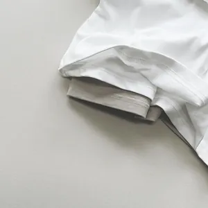 Dettaglio di una maglietta in cotone bianco con doppio scollo grigio e cuciture rifinite