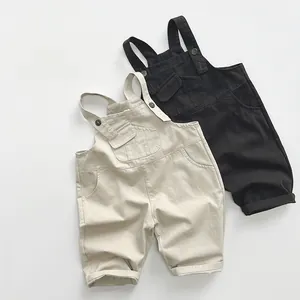 Détail de salopettes pour enfants en beige et noir avec bretelles boutonnées ajustables