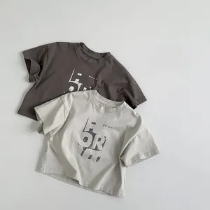 Gros plan de deux t-shirts en coton pour enfants en anthracite et beige avec imprimés rétro