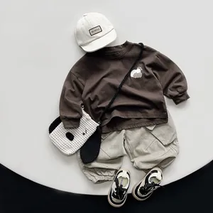 Flat lay of brown cotton children sweatshirt with apple print and beige cargo pants outfit